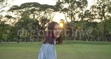 日落时分，年轻迷人的亚洲女人在一个夏天的公园里奔跑。 美丽的女孩在户外享受大自然。